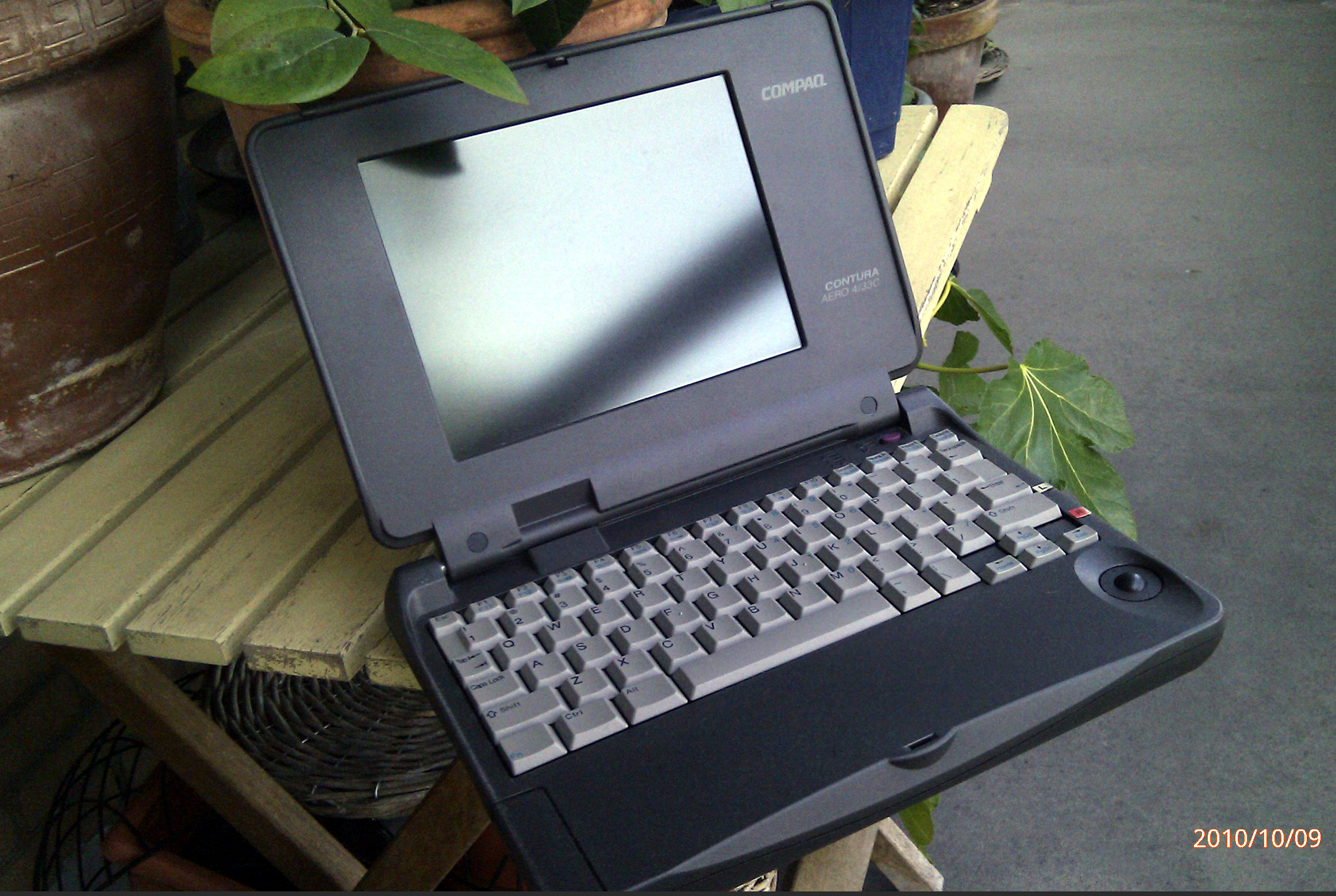 An open Compaq Contura Aero 4/33C laptop with a trackball beside the keyboard